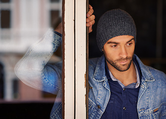 Image showing Man, window and thinking with fashion for dream, vision or memory in wonder or thought at home. Handsome male person or hipster looking out glass frame with beanie or denim clothing at the house