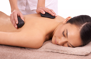 Image showing Hands, hot stone and woman with back massage at spa for wellness, self care and grooming treatment in studio. Skin, calm and female person with masseuse for warm rock body routine by white background