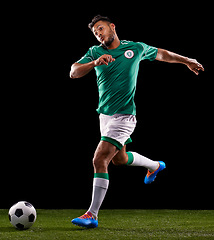 Image showing Man, ball and soccer for sport and fitness for game, active and sportswear on grass or field. Role model, athlete or player and practice for kick, competitive and score in night on dark background