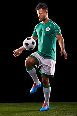 Image showing Man, ball and soccer for sport, balance and fitness for game, active and sportswear on grass or field. Professional, athlete or player and practice for competitive and score on dark background