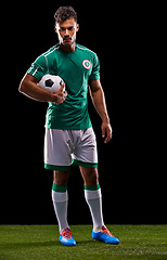 Image showing Man, ball and portrait for soccer, sport and match for fitness game and active for sportswear on grass or field. Professional or athlete and training with kit for competitive on dark background