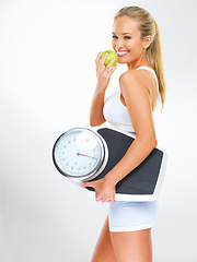 Image showing Woman, portrait and scale or apple for health, studio and excited for results of diet or detox. Female person, nutrition and journey for calories burned target, organic snack and white background