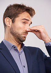 Image showing Entrepreneur, man and studio with smell or hand gesture on white background for stinky place and corporate. Closeup, businessman and nose closed for fart at with dislike in suit and professional