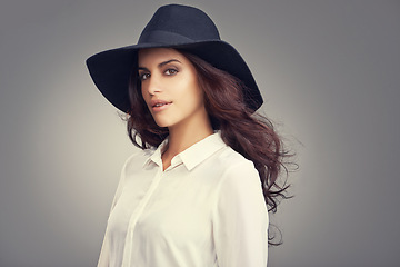 Image showing Fashion, beauty and portrait of woman in studio with classy, trendy and stylish hat for outfit. Confident, makeup and young female person with elegant style and accessory isolated by gray background.