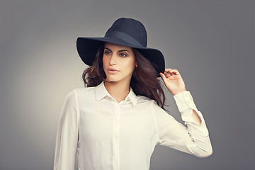 Image showing Fashion, thinking and young woman in studio with classy, trendy and stylish hat for outfit. Confident, makeup and female person with ideas for elegant style and accessory isolated by gray background.