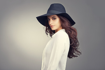 Image showing Fashion, makeup and portrait of woman in studio with classy, trendy and stylish hat for outfit. Confident, face and young female person with elegant style and accessory isolated by gray background.