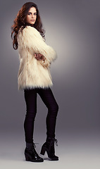 Image showing Fur coat, fashion or woman in studio or portrait for cool style, trendy jacket or comfortable outfit. Chic, winter or model with satisfaction in cosy, heels or casual clothing on grey background
