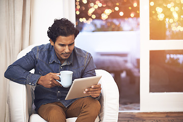 Image showing Tablet, coffee and man on sofa in living room for online blog on social media, app or internet. Reading, web and male person drinking cappuccino and scroll on digital technology in lounge at home.
