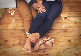 Image showing Wine, feet and couple relaxing together on wooden floor for romantic date at modern home. Love, champagne and closeup of man and woman legs with alcohol drink sitting on ground at apartment.