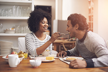 Image showing Breakfast, kitchen and woman feeding husband food for health, wellness and diet at home. Happy, love and young couple bonding and eating meal together on weekend morning at modern apartment.