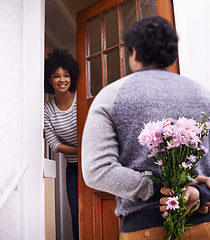 Image showing Flowers, surprise and happy couple at door of home for gift, love or care in relationship together. Bouquet, smile and man with present for woman on anniversary, celebration and romance with bunch