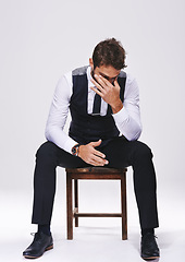 Image showing Stress, fashion and man in studio with suit for elegant, trendy and classy outfit with headache. Migraine, burnout and male person in tuxedo for fancy style on chair isolated by white background.