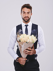 Image showing Man, studio and portrait in suit with flowers, Valentines day date with smile for happiness. Celebration, natural rose bouquet and gratitude and classy male person, black tie clothes with plant