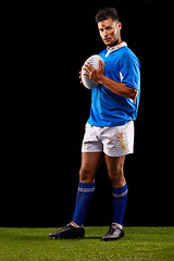 Image showing Rugby, background and portrait of man at night for training, competition and sportswear dark studio. Confidence, player and male athlete with ball for professional sport, workout or exercise on grass