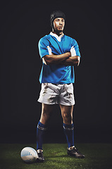 Image showing Studio, night and rugby man with arms crossed for competition, training or sportswear on dark background. Confident, athlete and person by ball for professional sport, workout or exercise on grass