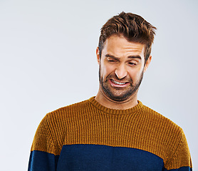 Image showing Man, face and problem with disgust in studio for dirty hygiene, smelling odor and negative body language. Person, shame or regret on white background for halitosis or upset expression on mockup space