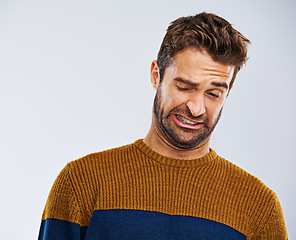 Image showing Man, frown and facial expression in studio for disgust and regret for attitude, emotion and mood. Male model and young person and isolated with face gesture or grimace for oops on white background