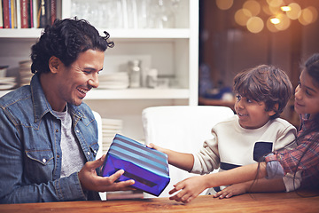 Image showing Father, children and present giving in home for happy birthday congratulations, celebration or gratitude. Male person, siblings and gift parcel at table for vacation connection, family or living room