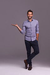 Image showing Happy man, portrait and presentation with palm for advertising, marketing or showcase on a gray studio background. Young and handsome male person or employee with smile showing option on mockup space