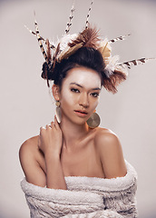 Image showing Woman, portrait and native american headdress in studio with feather, hair and beauty with culture cosmetics. Model, face and indigenous make up or art and elegant fashion or cloth on grey background