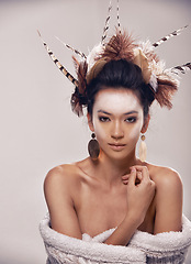 Image showing Model, portrait and native american headdress in studio with feather, hair and beauty with culture cosmetics. Woman, face and indigenous make up or art and elegant fashion or cloth on grey background