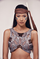 Image showing Portrait, woman and Native American culture in studio with warrior makeup, confidence and tribe style. Indigenous fashion, face paint or girl in First Nations clothes on white background with feather