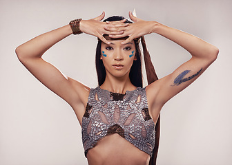 Image showing Portrait, woman and Native American style in studio with warrior makeup, confidence and tribe culture. Indigenous fashion, face paint or girl in First Nations clothes on white background with feather