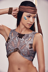 Image showing Face, woman and Native American culture in studio with warrior makeup, confidence and tribe style. Indigenous fashion, creative and girl in First Nations clothes on white background with feather