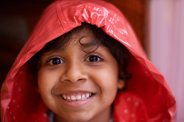 Image showing Happy boy, portrait and fashion with red raincoat for rain, winter or cold season at home. Face of cute young child or kid with smile for protection, clothing or safety from rainy weather at house