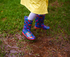 Image showing Feet, puddle and boots of kid playing in rain soil for forest, adventure or explore games in nature closeup. Earth, mud and shoes of child in woods for walking, camping or travel, holiday or vacation