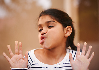 Image showing Window, face and funny girl with cheek press comic in her house with silly, joke or goofy gesture. Glass, mouth or Indian child with humor, games or playing on vacation, holiday or weekend in India