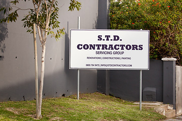 Image showing Contractor, poster and sign for advertising, outdoor and mistake with grammar, humor and comic text on lawn. Real estate group, board and error with language, houses and construction company on grass