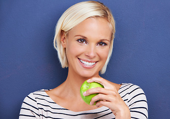 Image showing Woman, portrait and apple in studio or healthy diet on blue background or fruit nutrition, snack or fibre. Female person, relax and wellness eating or mockup space as vegan detox, food or lose weight