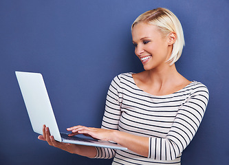 Image showing Woman, smile and laptop in studio for research, internet and online for relax and website for break indoor. Young person or freelancer and happy with tech for typing, email and connection on mockup