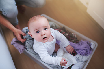 Image showing Laundry, washing and portrait of baby in basket in home for multitasking, housekeeping and housework. Family, childhood and above of parent with newborn for cleaning, hygiene and maintenance on floor