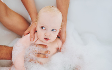 Image showing Soap, bubbles and baby in bath for cleaning, washing and hygiene with hands of parents in home. Family, bathroom and newborn infant in bathtub, foam and water for wellness, health and childcare