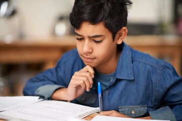 Image showing Student, boy and reading in home for study with thinking, problem solving and homework assessment by table. Child, education or knowledge with books in dining room for concentration on school project