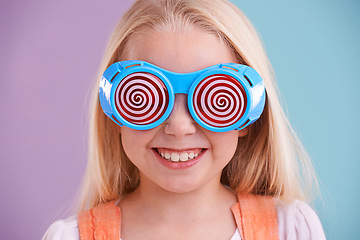 Image showing Child, studio and colour with fashion glasses, happy smile on girl with hypnotic cute eyewear. Groovy, funky and playful hipster style, trendy kid with cool vibrant bright pattern for accessories