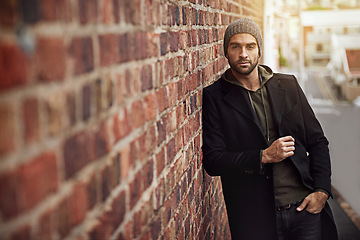 Image showing Man, portrait and urban style by brick wall downtown for aesthetic, modern and vacation for city culture. Male person, trendy winter outfit for streetwear fashion for creative career in New York