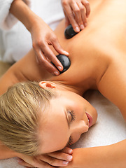 Image showing Woman, hot stone massage and spa with hands of masseuse, peace and treatment for destress at luxury resort. Serene, zen and calm with stress relief, self care and wellness with warm rocks for detox