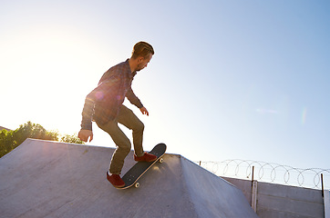 Image showing Skate park, freedom and man with skateboard balance, stunt or bowl trick outdoor for training at sunset. Skating, energy and male skater with ramp action, performance or vacation fun or practice