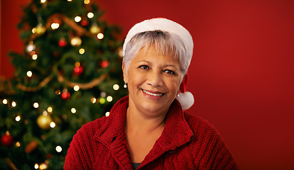 Image showing Christmas, smile and face of senior woman in studio for holiday celebration by tree isolated on a red background mockup space. Xmas, mature and happy female person in hat for festive season in Brazil