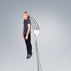 Image showing Depression, boy and sad on fork in studio, abstract and teenager with problem or mental health. Child, silver cutlery and kitchenware for weird concept of anxiety and adolescent with fear or worry