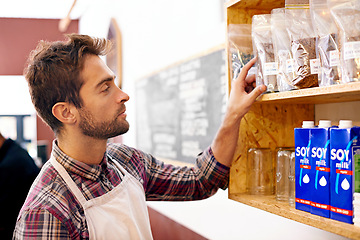 Image showing Man, barista and check by shelf in a coffee shop with idea for service, search or ingredients for drink. Waiter, person or small business owner in a cafe with product, beans and thinking for decision