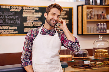 Image showing Man, coffee shop and cell phone call with smile for contact, deal or order for drink at small business. Person, barista or waiter with smartphone for conversation, networking and happy in cafeteria