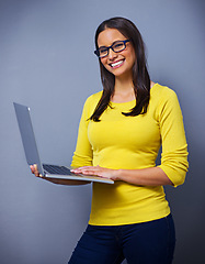 Image showing Woman, laptop and smile in studio for portrait with freelance job, writing and editing by blue background. Girl, person or journalist with computer for story, news or magazine with research in Mexico