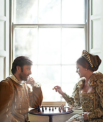 Image showing Renaissance, couple and chess at home with talking, vintage and medieval costume in a palace. Window, luxury and queen together with smile from strategy game and talking while playing with love