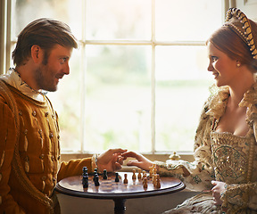 Image showing Renaissance, couple and chess at home with holding hands, vintage and medieval costume in a palace. Window, luxury and queen together with smile from strategy game and talking while playing with love