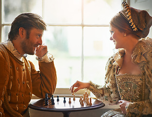 Image showing Renaissance, couple and chess at home with smile, vintage and medieval costume in a palace. Window, luxury and queen together with smile from strategy game and talking while playing with love