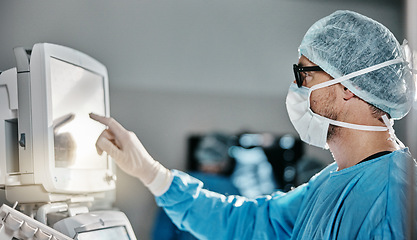 Image showing Doctor, scrubs and monitor with machine in theatre for surgery, cardiology analysis and information. Medical, man and digital technology in hospital for operation, procedure or healthcare examination